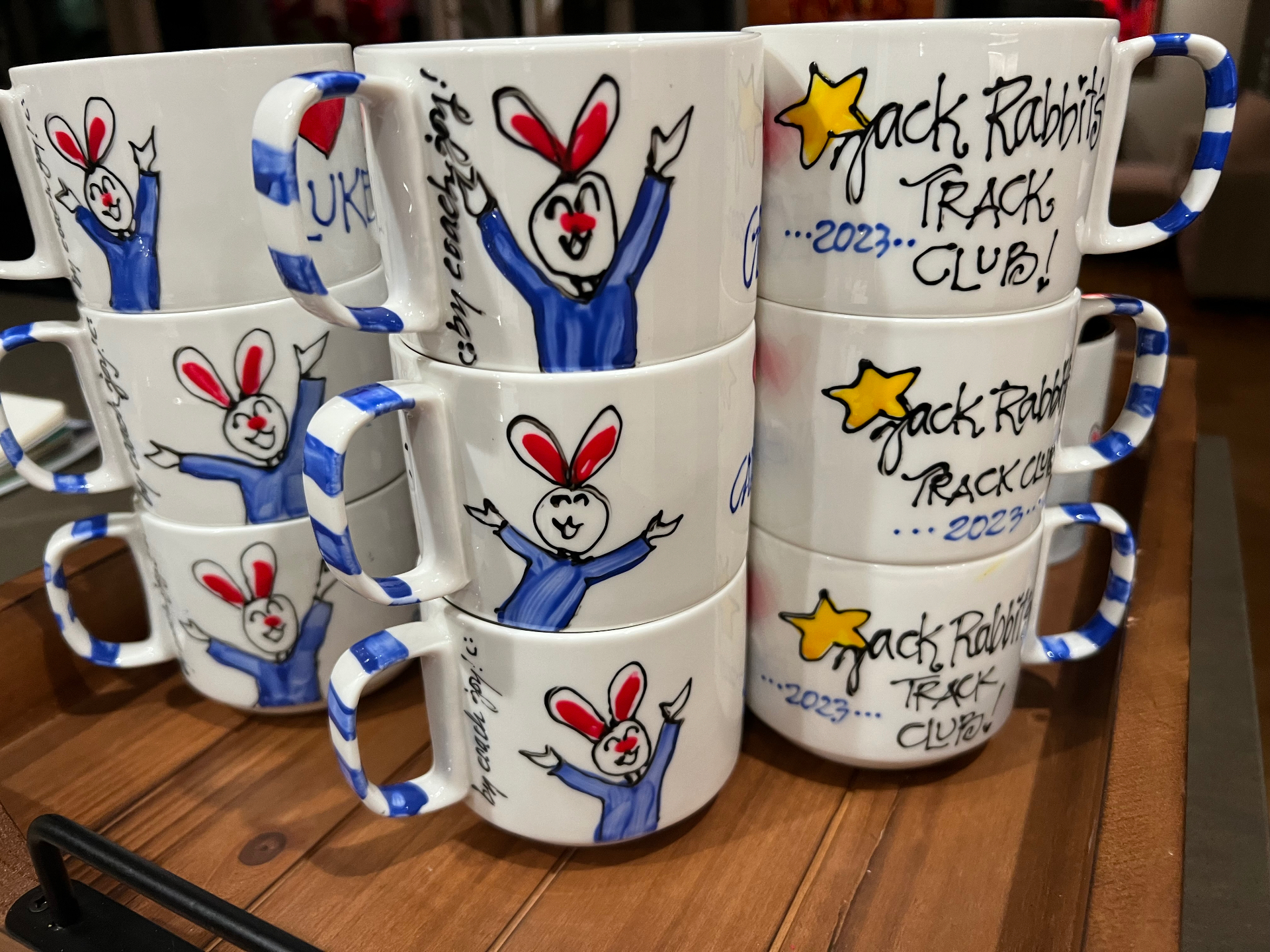 Hand painted mugs showing a cheering rabbit in blue, signed by Coach Joy